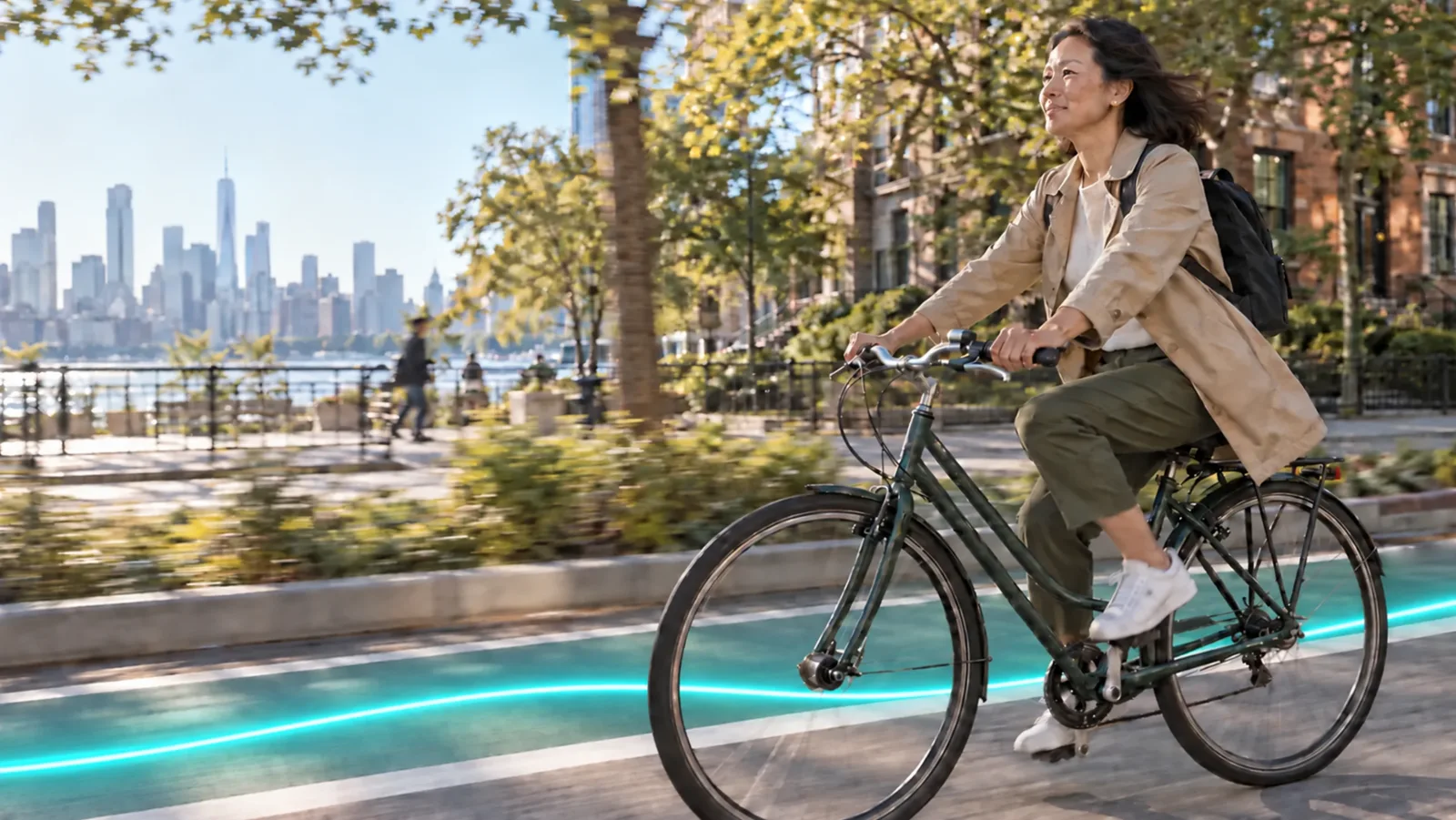 A woman cycling along a waterfront path on a sunny morning